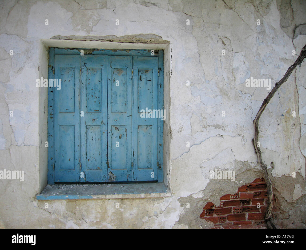 Blauen Fensterläden Fenster in beschädigten weiße Wand mit crack auszusetzen rote Ziegeln Stockfoto