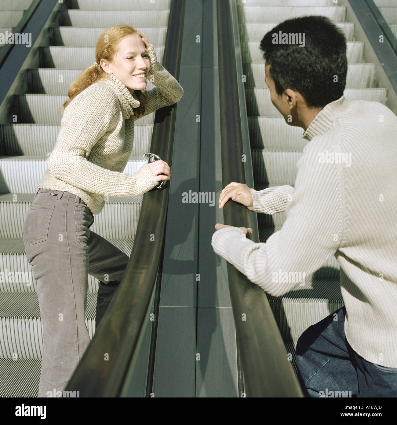 Junger Mann und junge Frau auf Rolltreppen Stockfoto