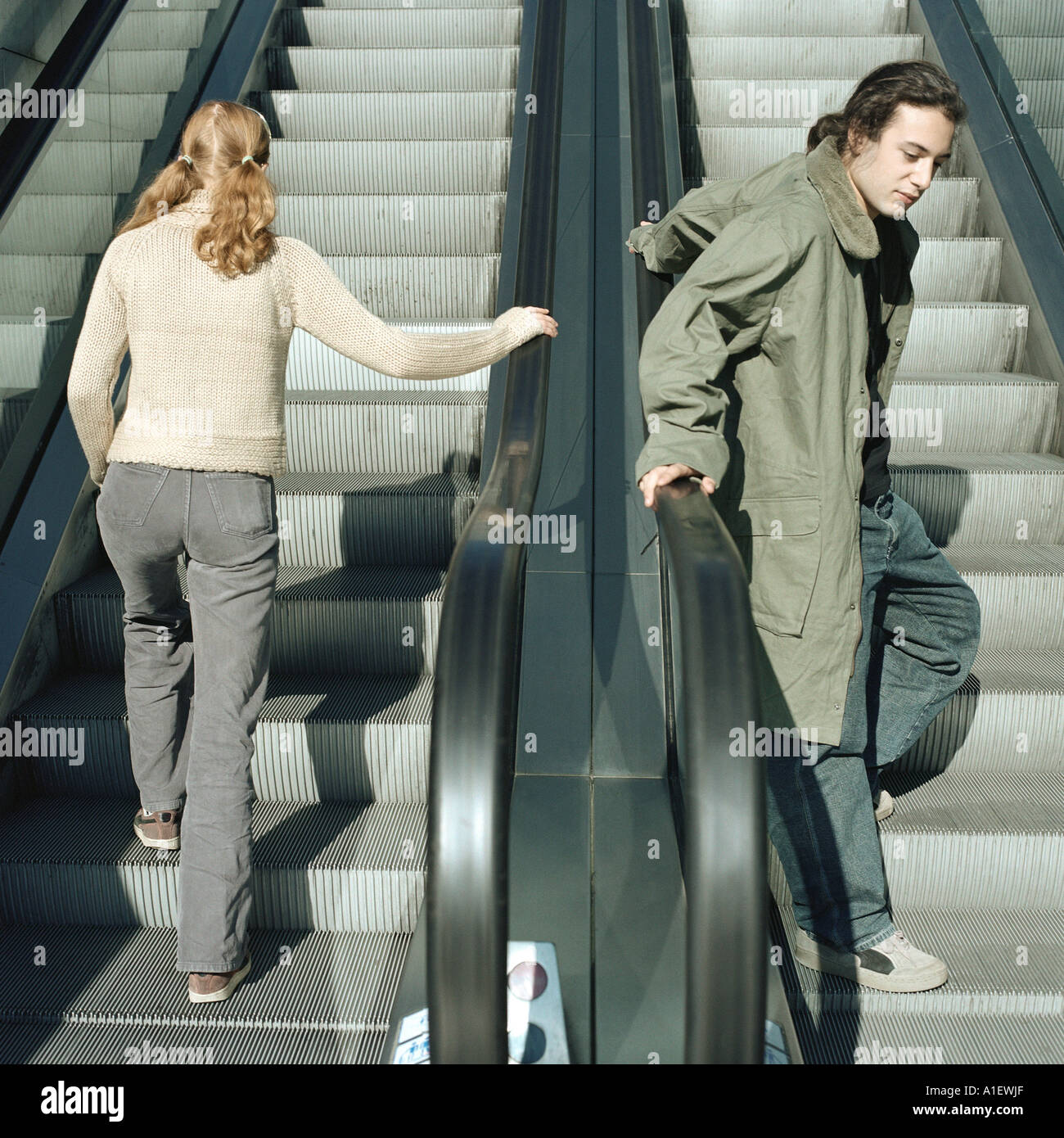 Junger Mann und junge Frau auf Rolltreppen Stockfoto