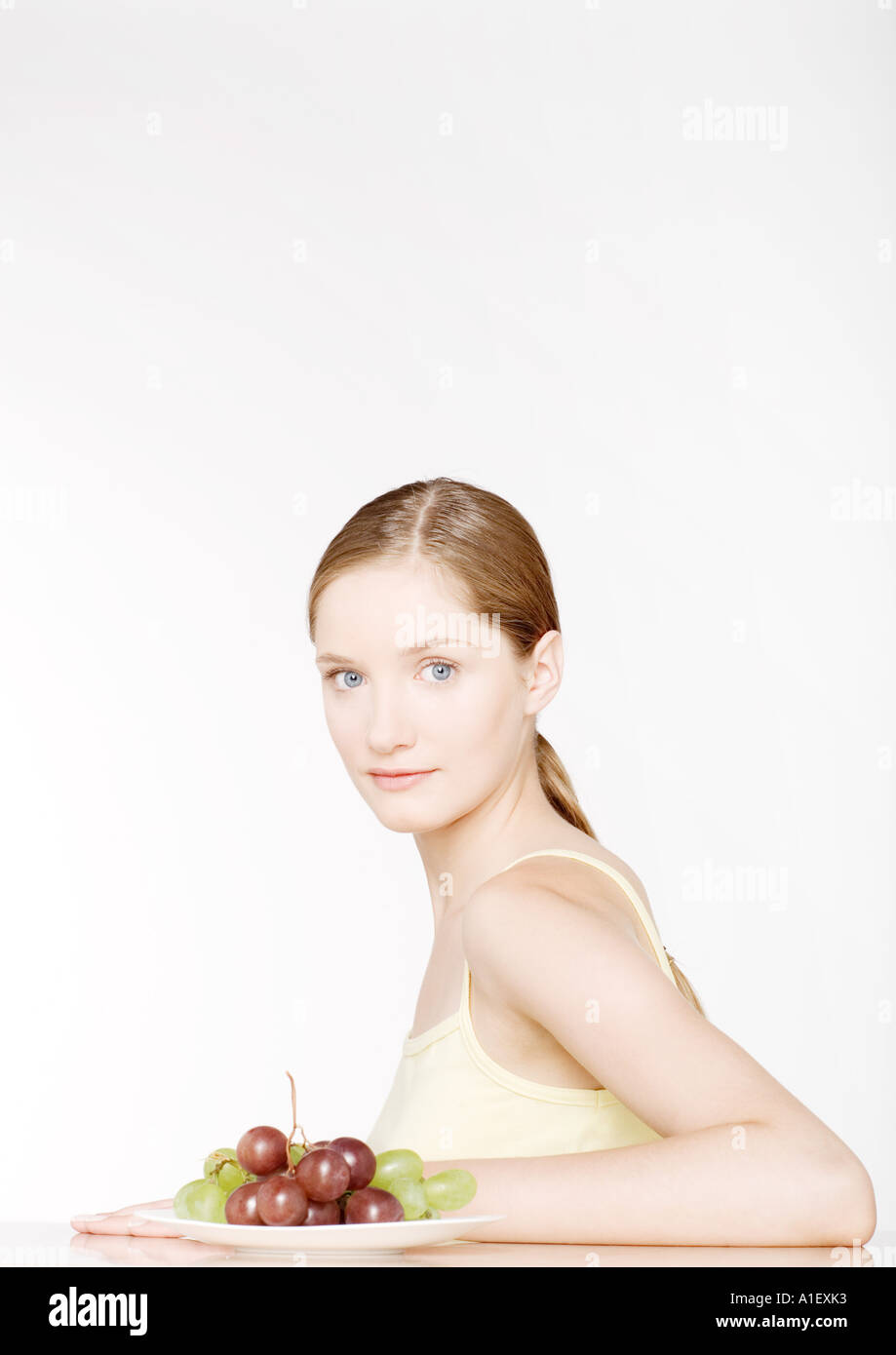 Frau sitzt mit Teller mit Trauben Stockfoto