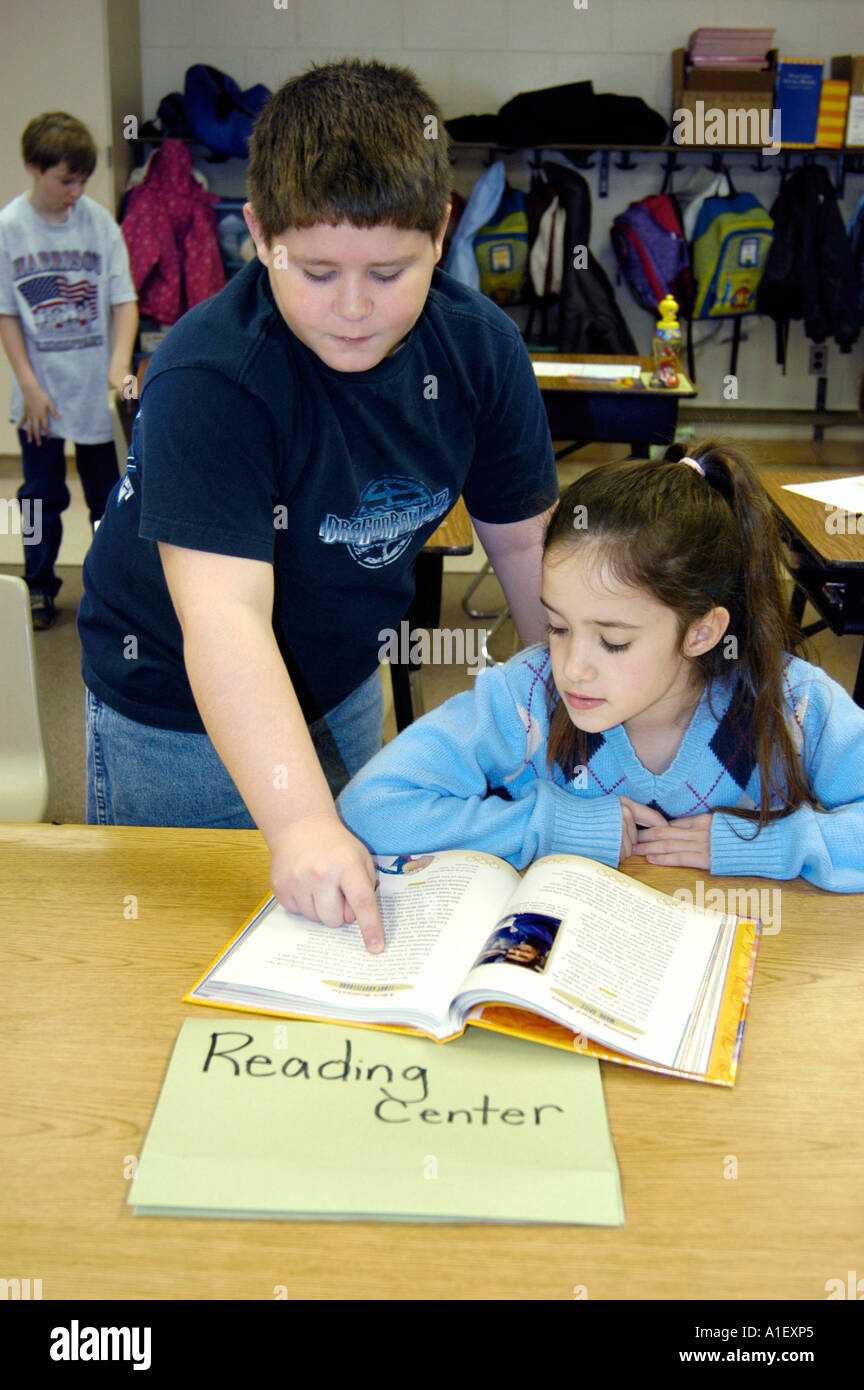 Junge hilft Studentin in einer Lesung Mitte in einer Lernsituation Grundschule Stockfoto