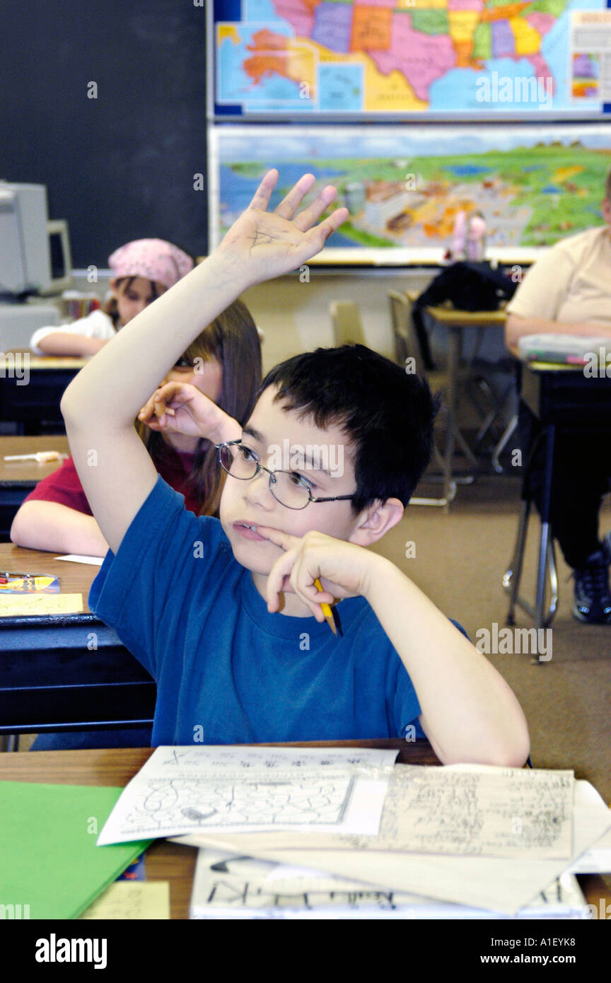 Jungen und Mädchen Studenten in einer Grundschule lernen Schüler Situation mit Hand angehoben, um Fragen oder eine Frage zu beantworten Stockfoto