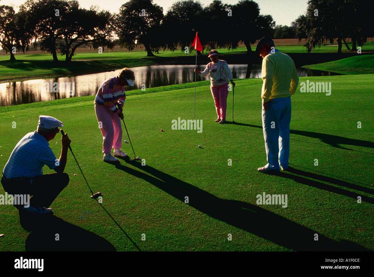 Zwei Paare im Ruhestand, Golfen auf Putting green Stockfoto