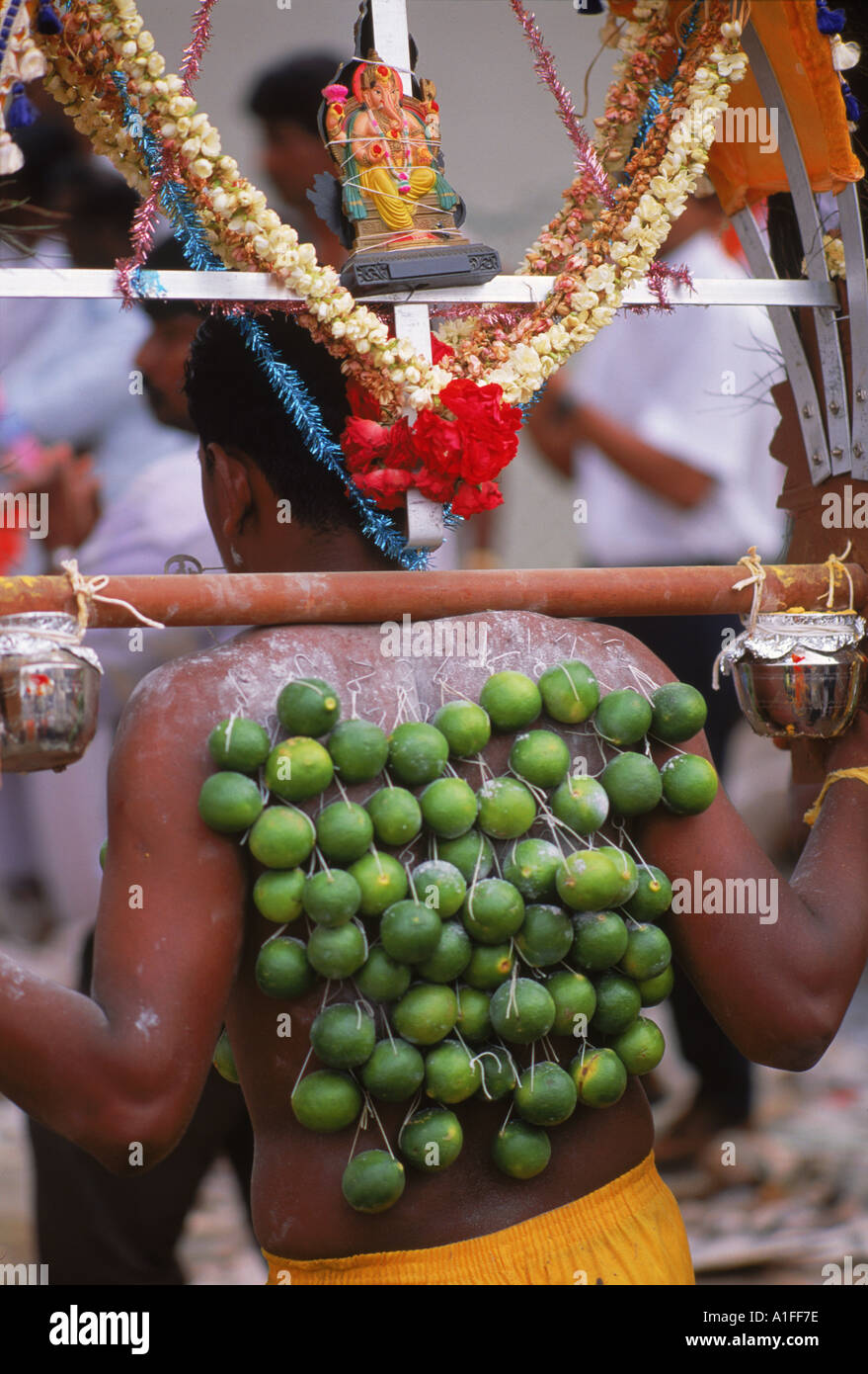 Nahaufnahme eines Mannes Apos s wieder mit Limetten am Haken in seine Haut und eine kleine Statue von Ganesh über seinem Kopf während des Festivals Stockfoto