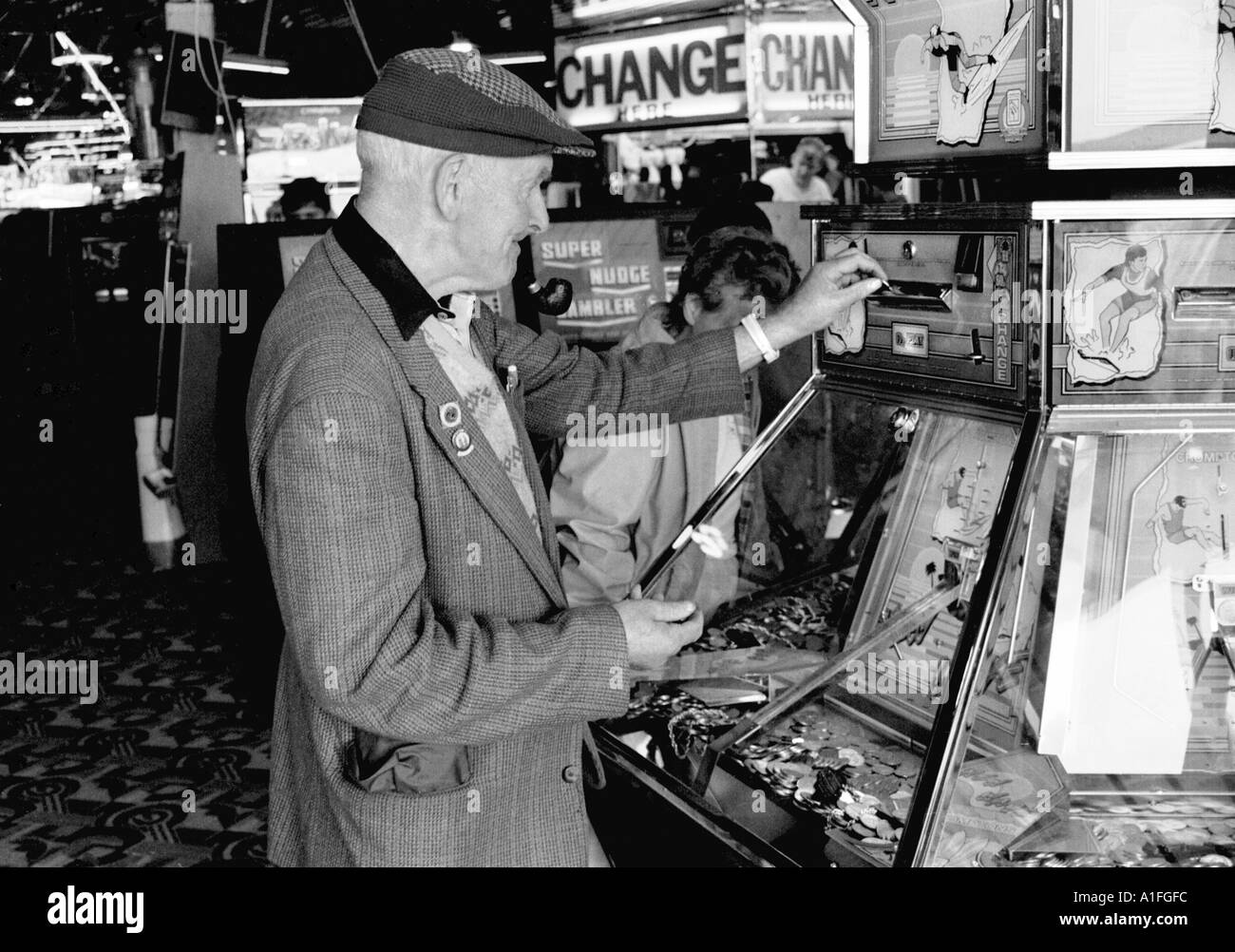 Alter Mann in flache Kappe, Geld in Spielautomaten im Meer Spielhalle in Scarborough in North Yorkshire schwarz und whi Stockfoto