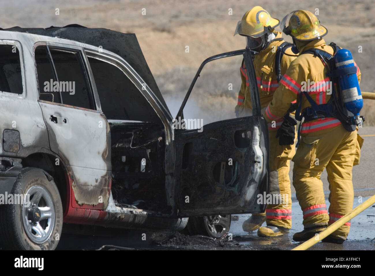 Brennenden Auto und Feuerwehrleute Stockfoto
