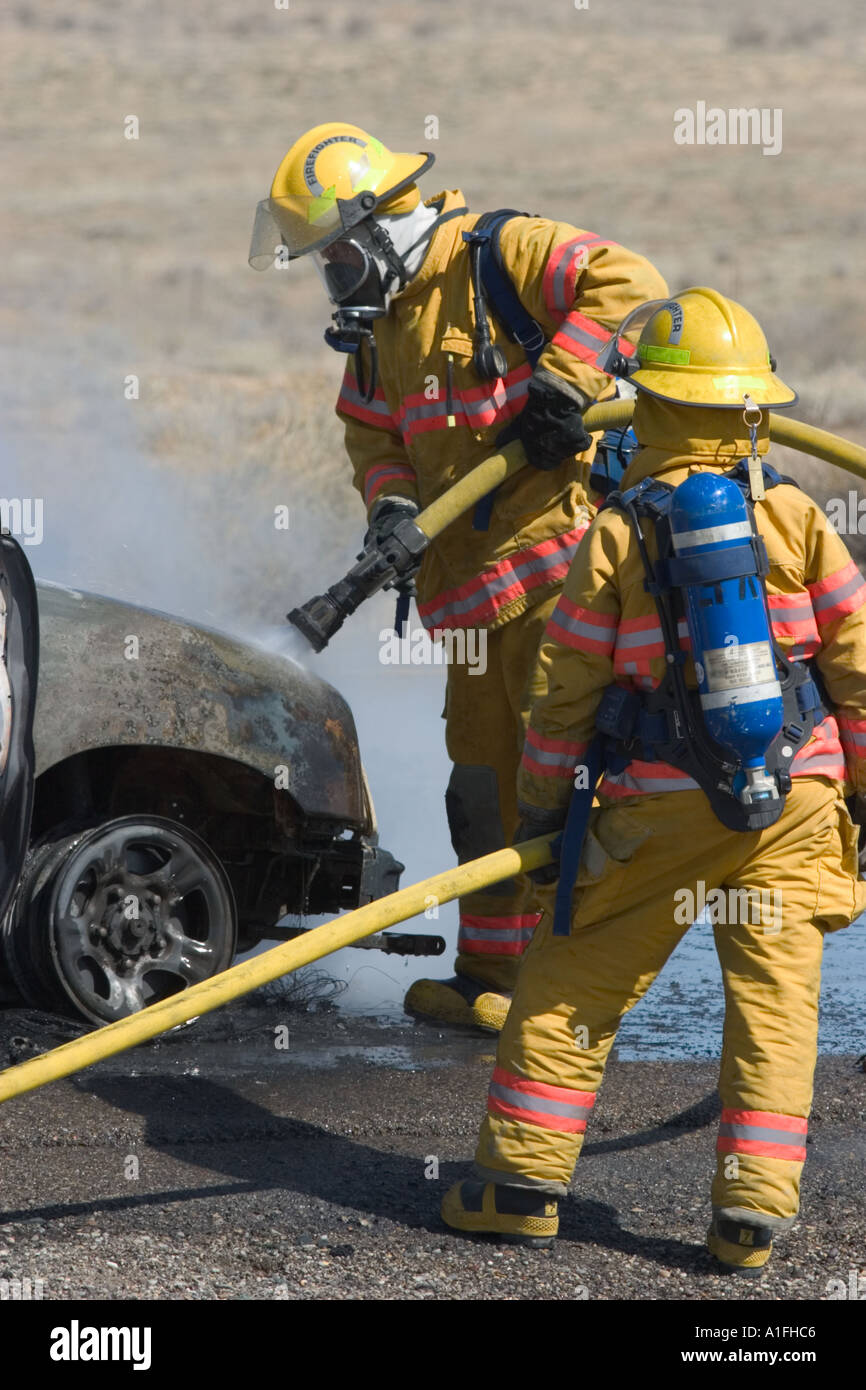 Brennenden Auto und Feuerwehrleute Stockfoto