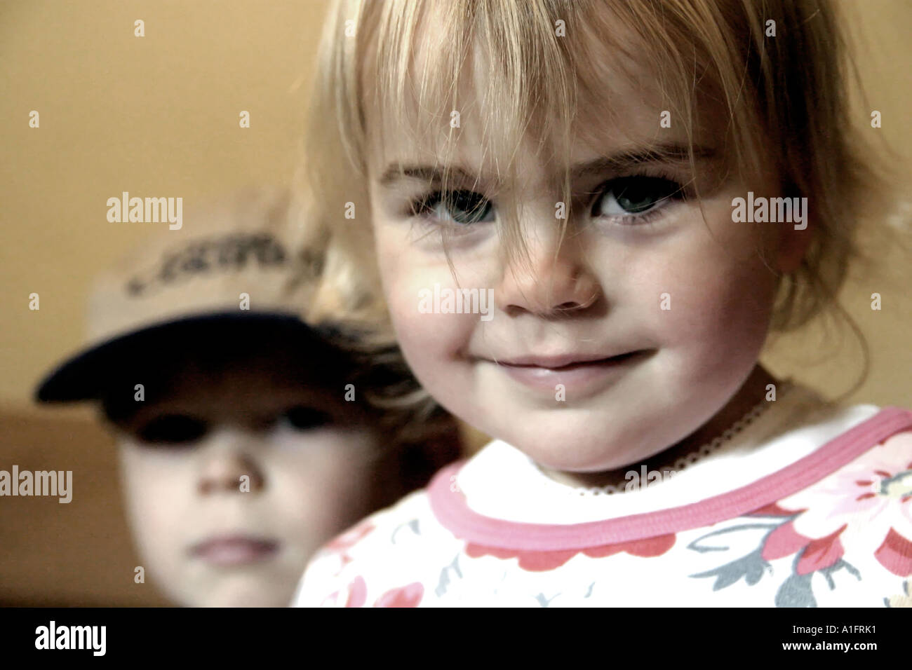 Mädchen im Alter von zwei Blick in Kamera mit jungen im Alter von fünf im Hintergrund Stockfoto