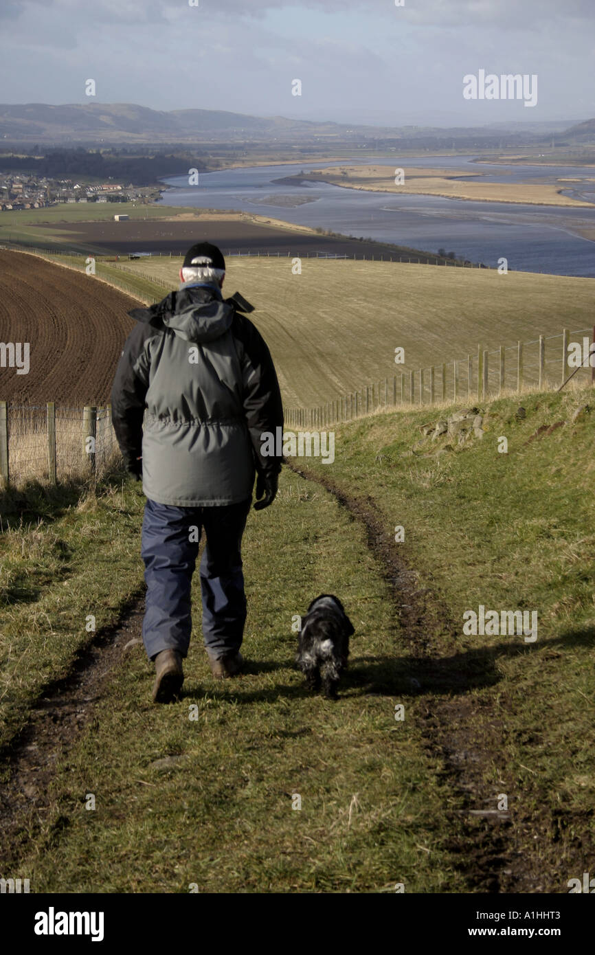 Mann geht mit seinem Hund in Fife Schottland mit Fluss Tay im Hintergrund Stockfoto