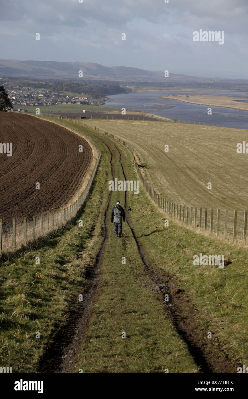 Entfernte Figur eines Mannes zu Fuß mit seinem Hund in Fife Schottland, Vereinigtes Königreich Stockfoto