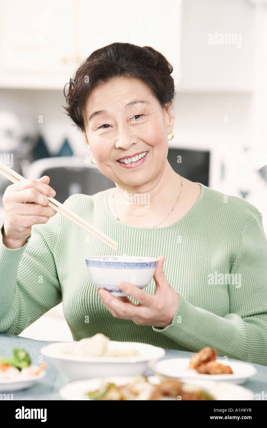 Porträt einer älteren Frau mit einem Paar Stäbchen und eine Schüssel Stockfoto