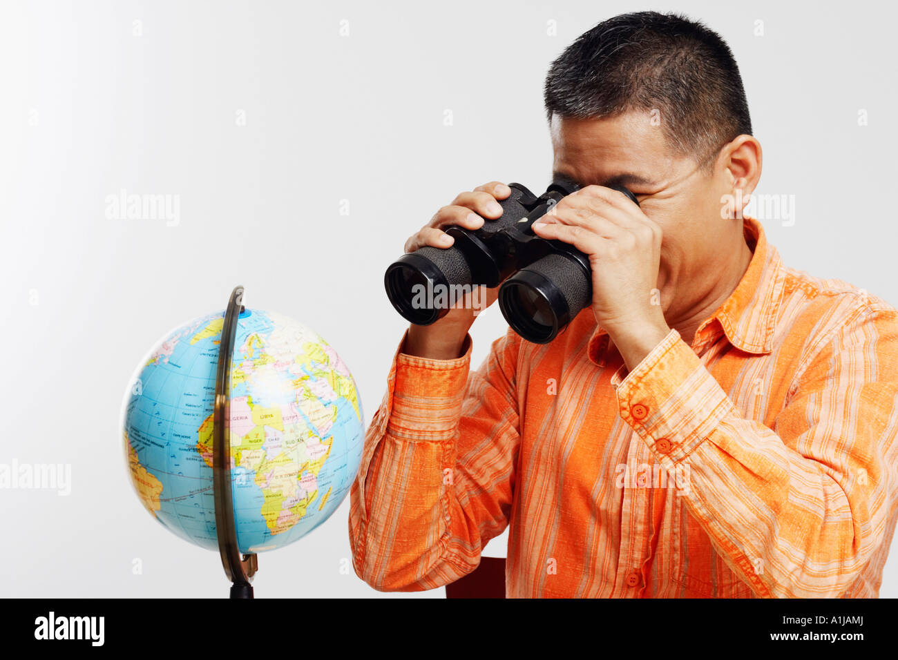 Nahaufnahme eines Mitte erwachsenen Mannes ein Tischglobus durch ein Fernglas betrachten Stockfoto