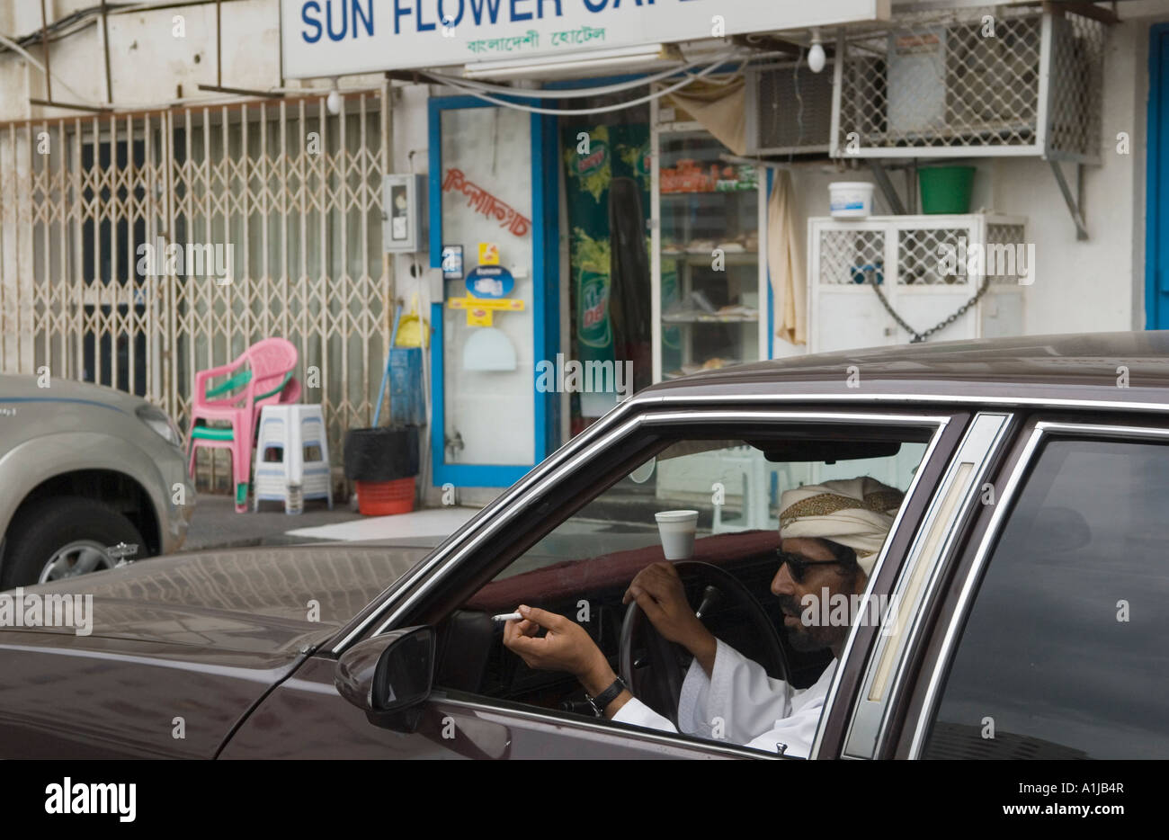 Abu Dhabi Vereinigte Arabische Emirate VAE gewöhnliche armer Straßenszene Mann sitzen im Auto rauchen flicking Asche aus Autofenster HOMER SYKES Stockfoto
