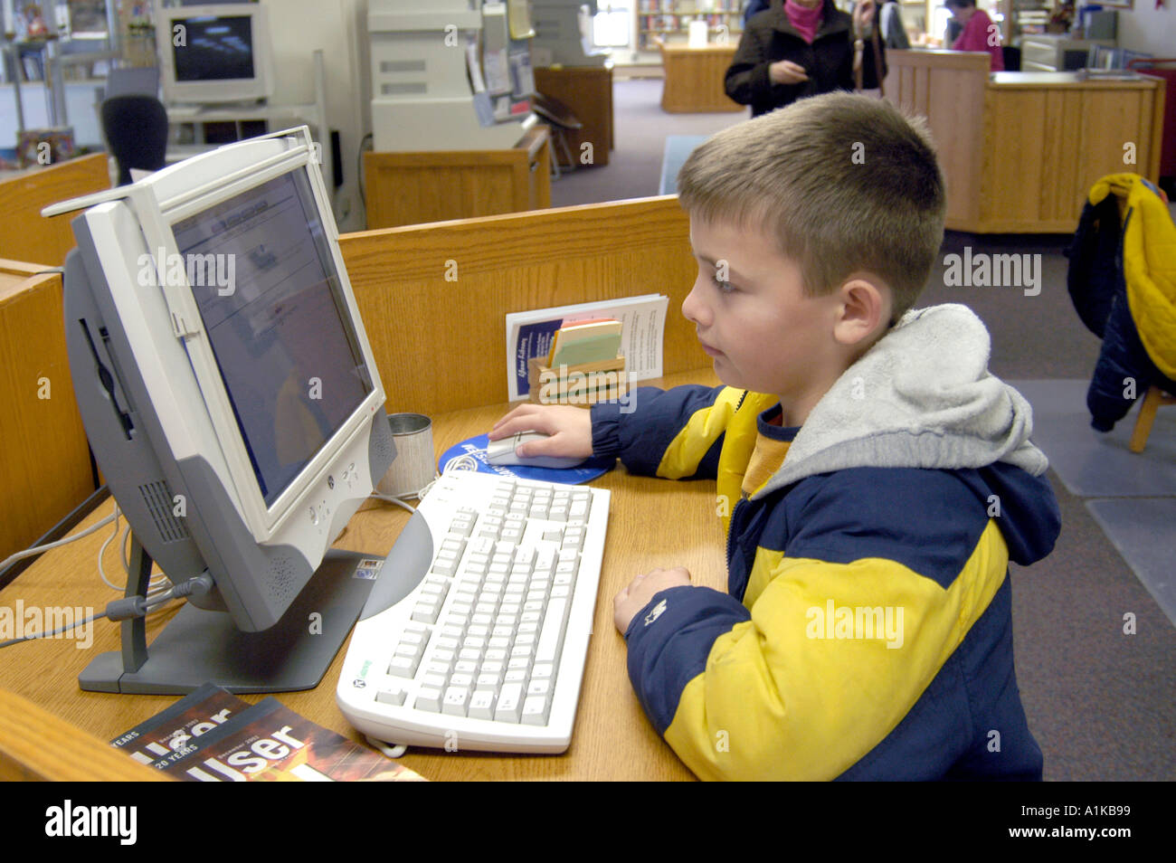 9-jähriger Junge verwendet Computer Zettelkatalog in der Bibliothek Stockfoto