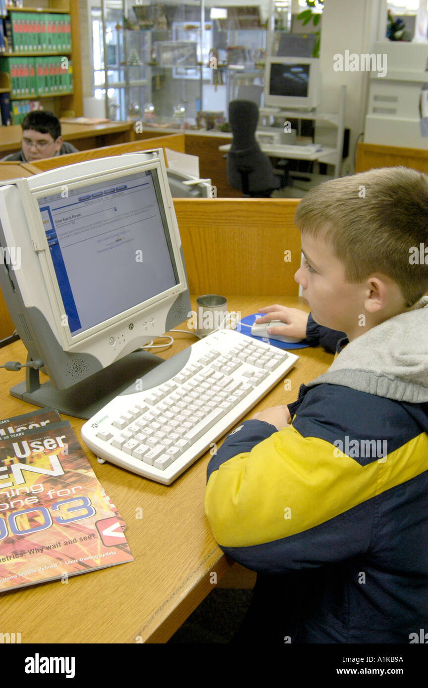 9-jähriger Junge verwendet Computer Zettelkatalog in der Bibliothek Stockfoto