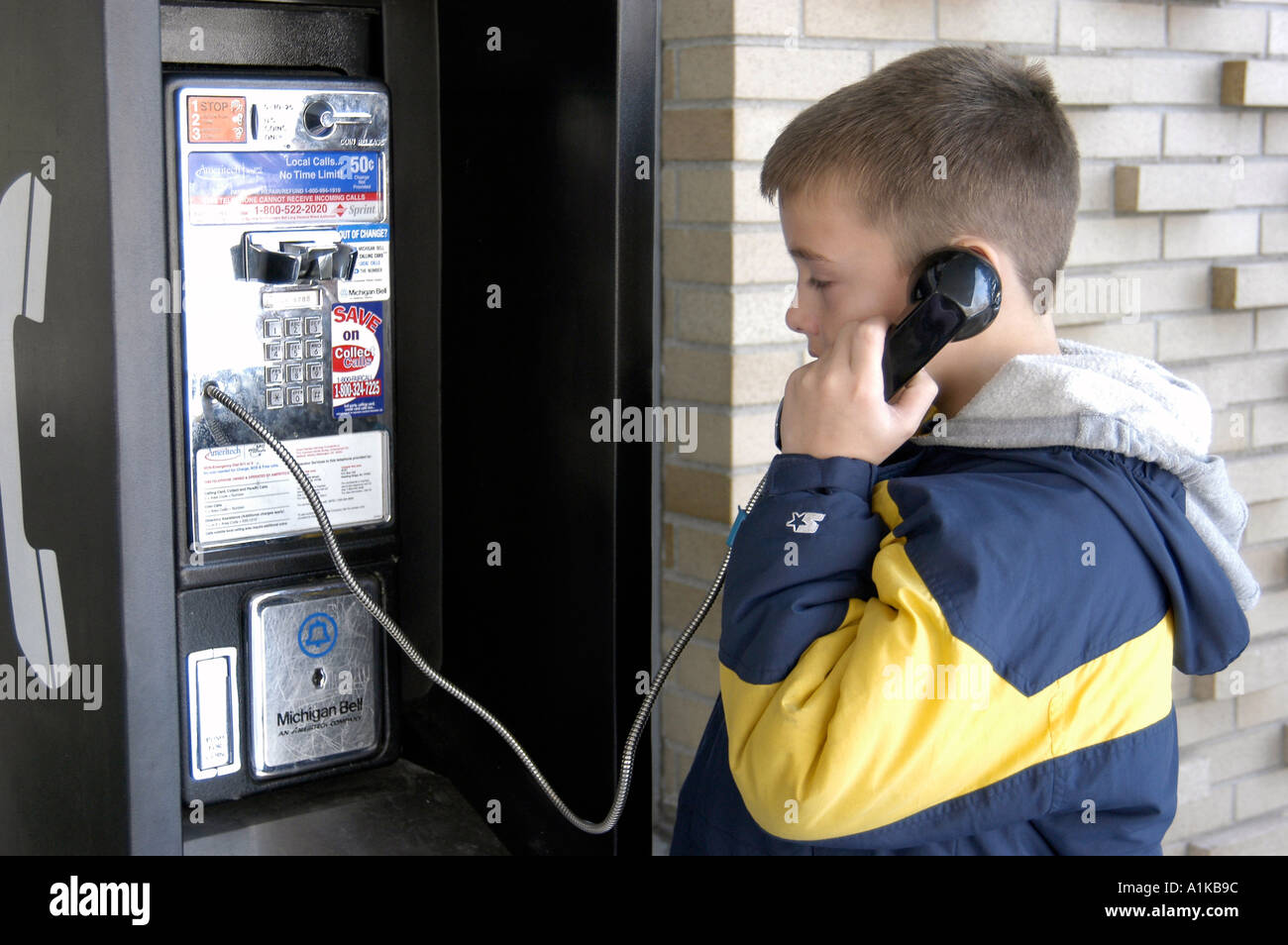 9 Jahre alter Junge verwendet Münztelefon Stockfoto