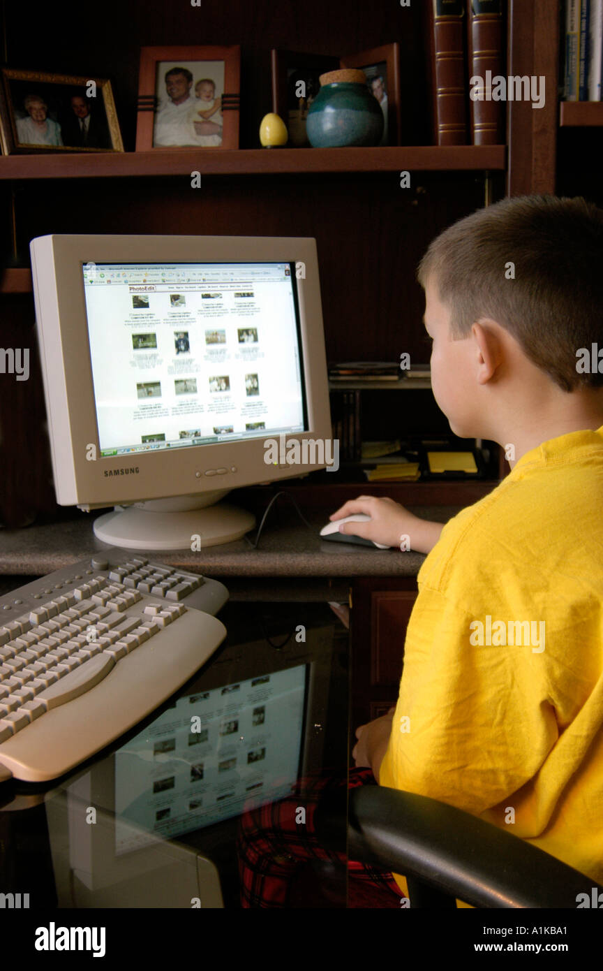 9 Jahre alter Junge auf einem Heimcomputer funktioniert Stockfoto