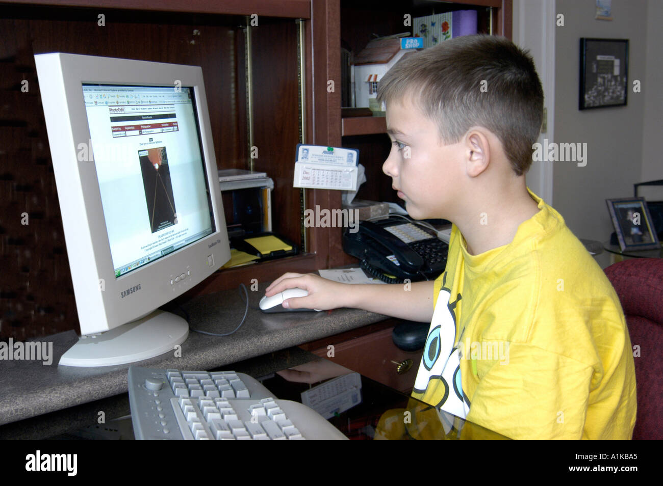 9 Jahre alter Junge auf einem Heimcomputer funktioniert Stockfoto