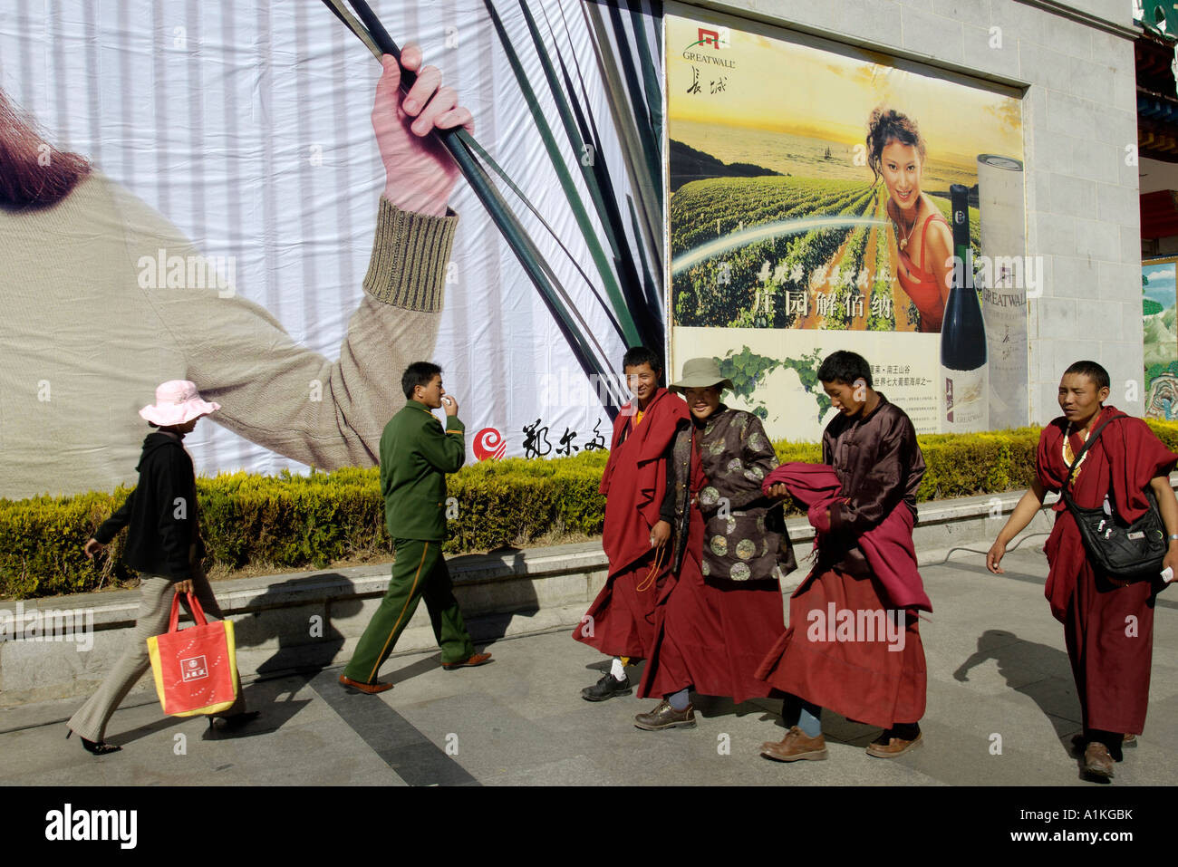 Eine Gruppe von tibetischen Mönchen vorbeigehen ein PLA-Mann und eine trendige Dame eine kommerzielle Plakatwand in Lhasa-Tibet 19. Oktober 2006 Stockfoto