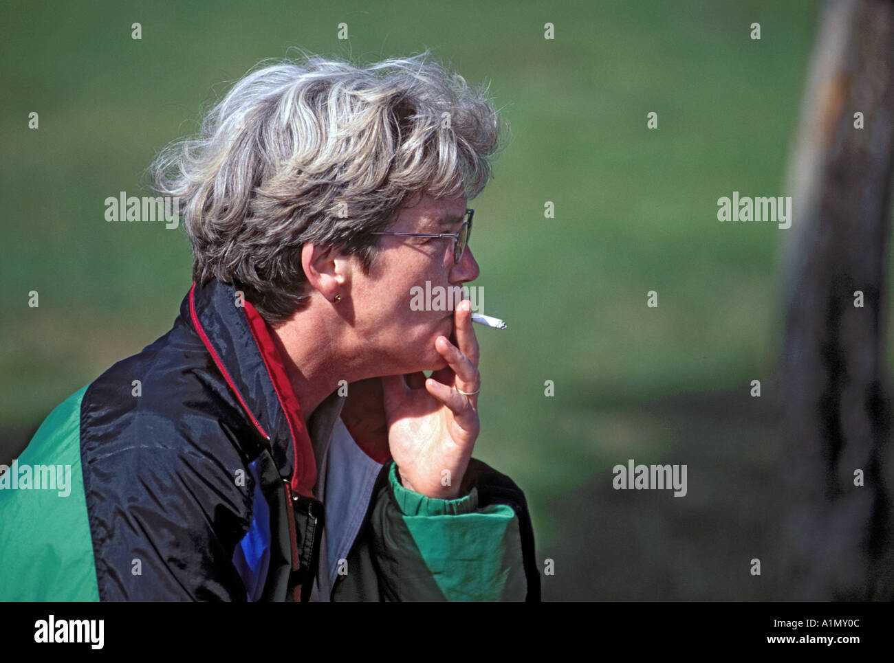 Senior rauchende Frau in Mantel Stockfoto