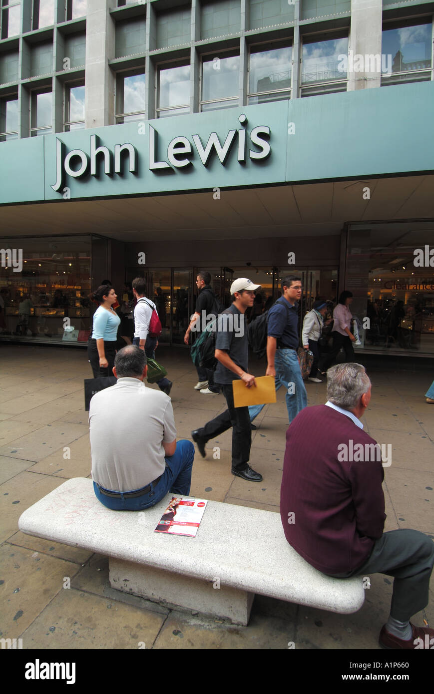 Street Scene London West End, Oxford Street Käufer außerhalb John Lewis Department Store Front mit Männer sitzen auf Stein Sitz England Großbritannien Stockfoto