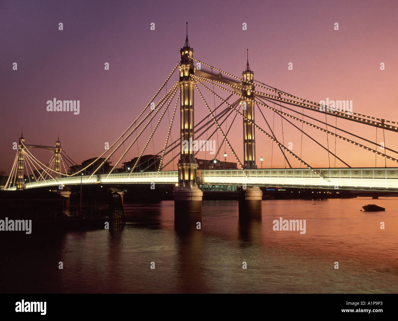 Sonnenuntergang und Licht in der Dämmerung auf der historischen viktorianischen Albert Bridge verbindet Chelsea im Norden mit Battersea im Süden der Themse London England Großbritannien Stockfoto