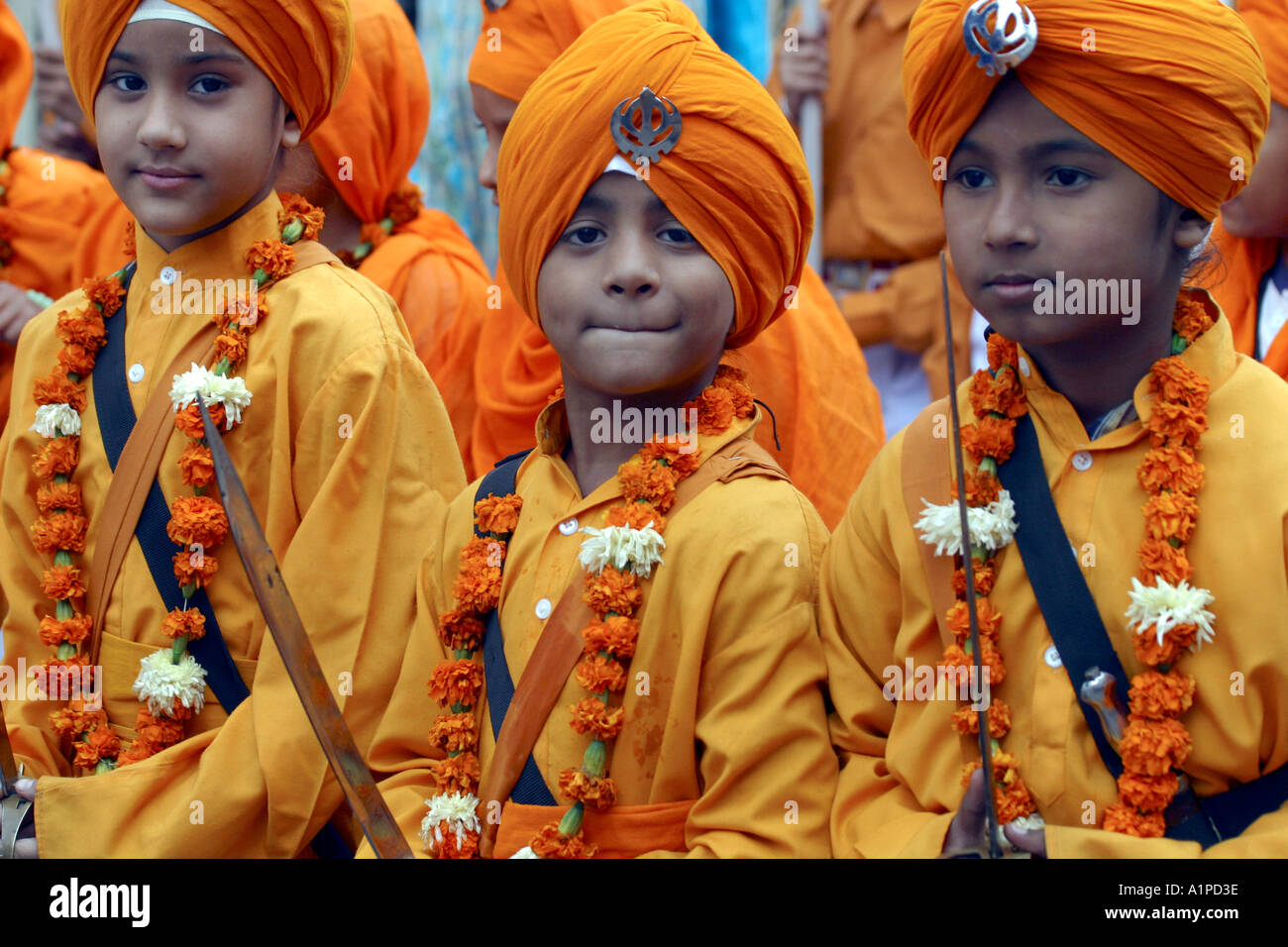 Eine Gruppe von jungen indischen Sikh Jungs mit Schwertern und tragen gelbe Turbane während einer Prozession Straße in Delhi in Indien Stockfoto