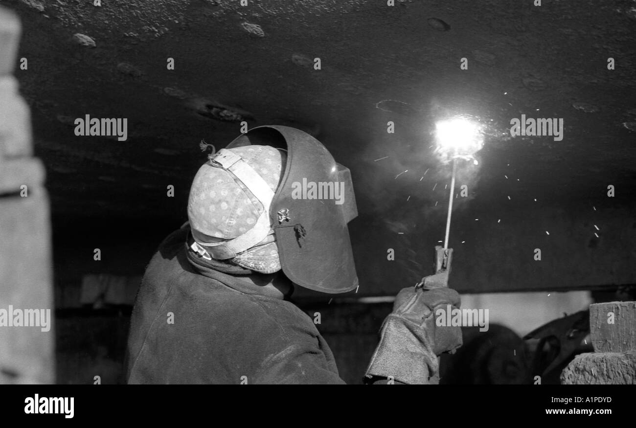 Arbeiter Schweißen machen Reparaturen an der Unterseite eines Trawlers in Grimsby. Stockfoto