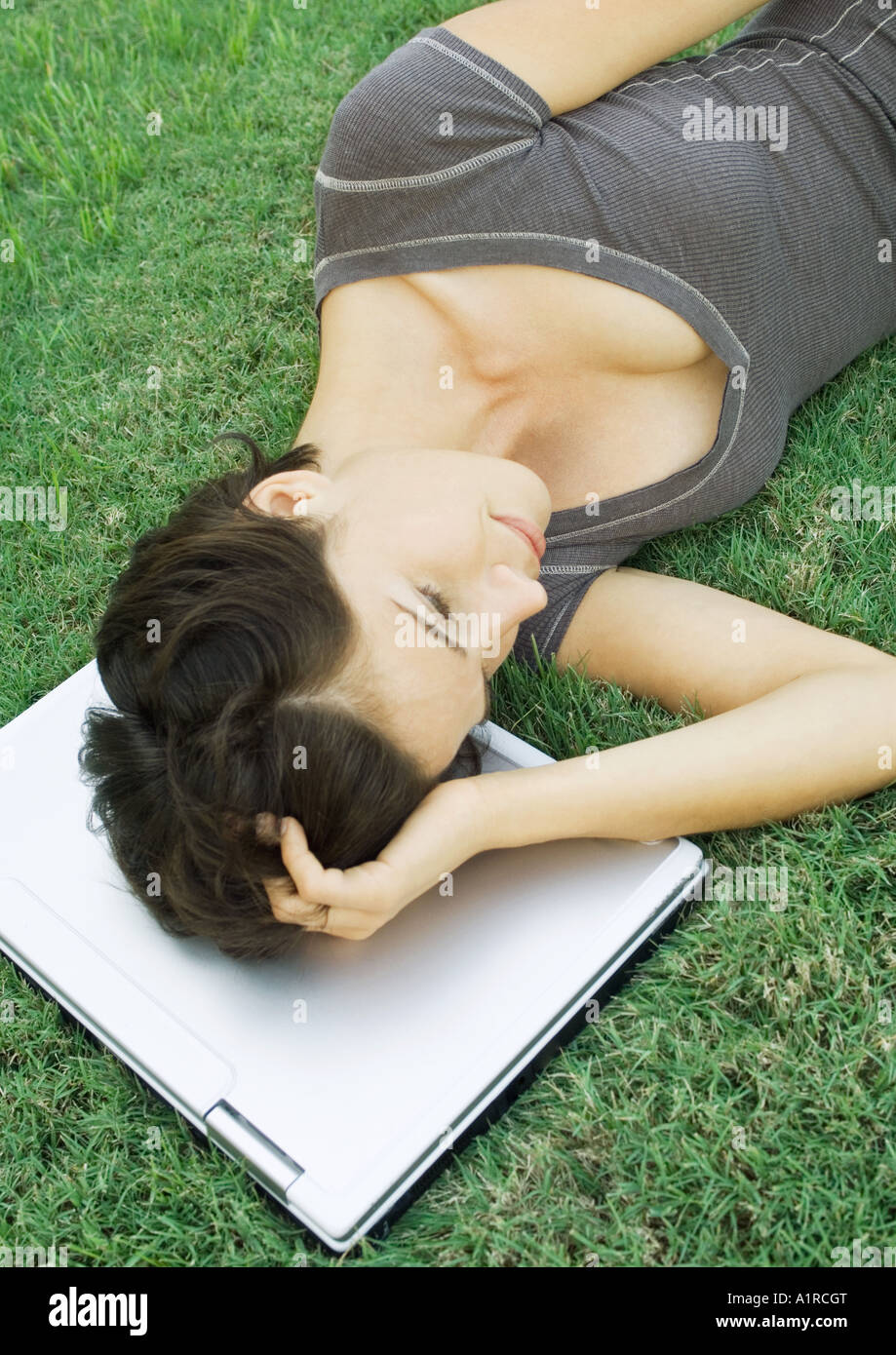 Frau liegend auf Rasen mit Kopf auf laptop Stockfoto