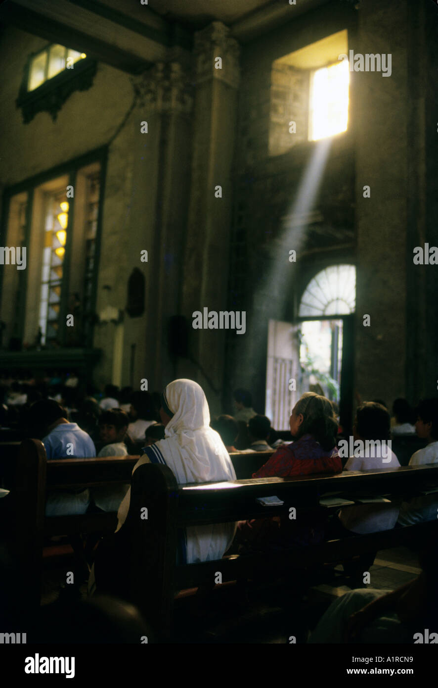 Eine Frau betet in der Kirche als ein Strahl von Licht scheint durch das Fenster dieses Bild eine spirituelle Wirkung verleihen. Stockfoto