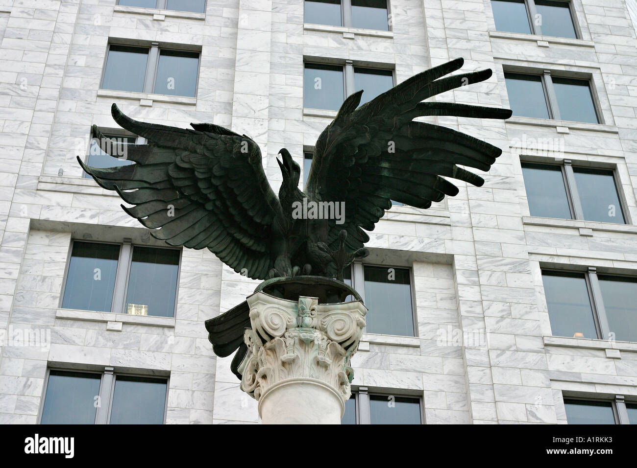 Adler und Büro: eine Bronze-Skulptur eines Adlers mit einem Hintergrund von Bürofenstern inmitten einer Marmorfassade Federal Reserve Bank Stockfoto