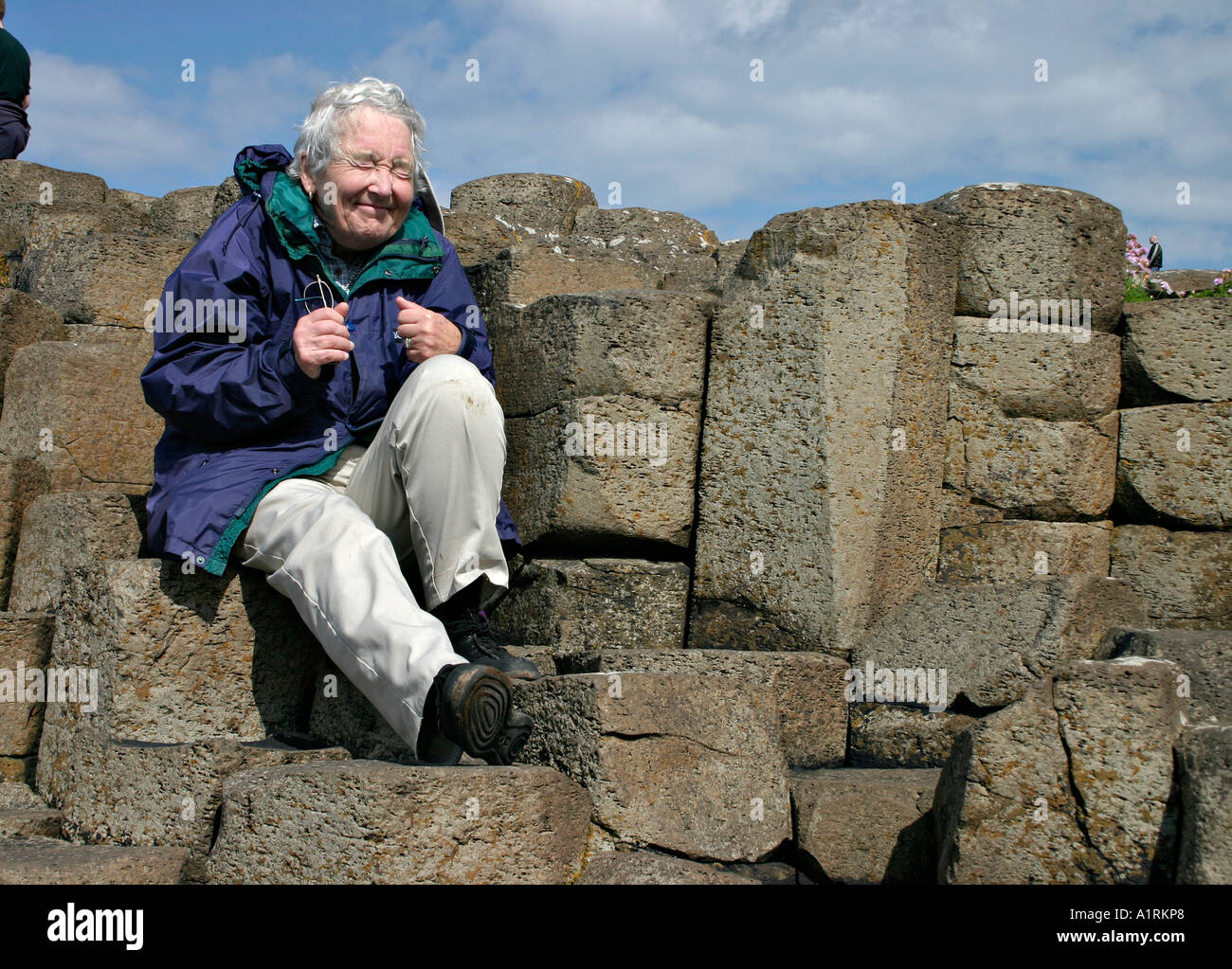 Machen einen Wunsch. Eine ältere Frau sitzt auf dem Wunsch Felsen und macht einen Wunsch, wie sie vor 65 Jahren Stockfoto