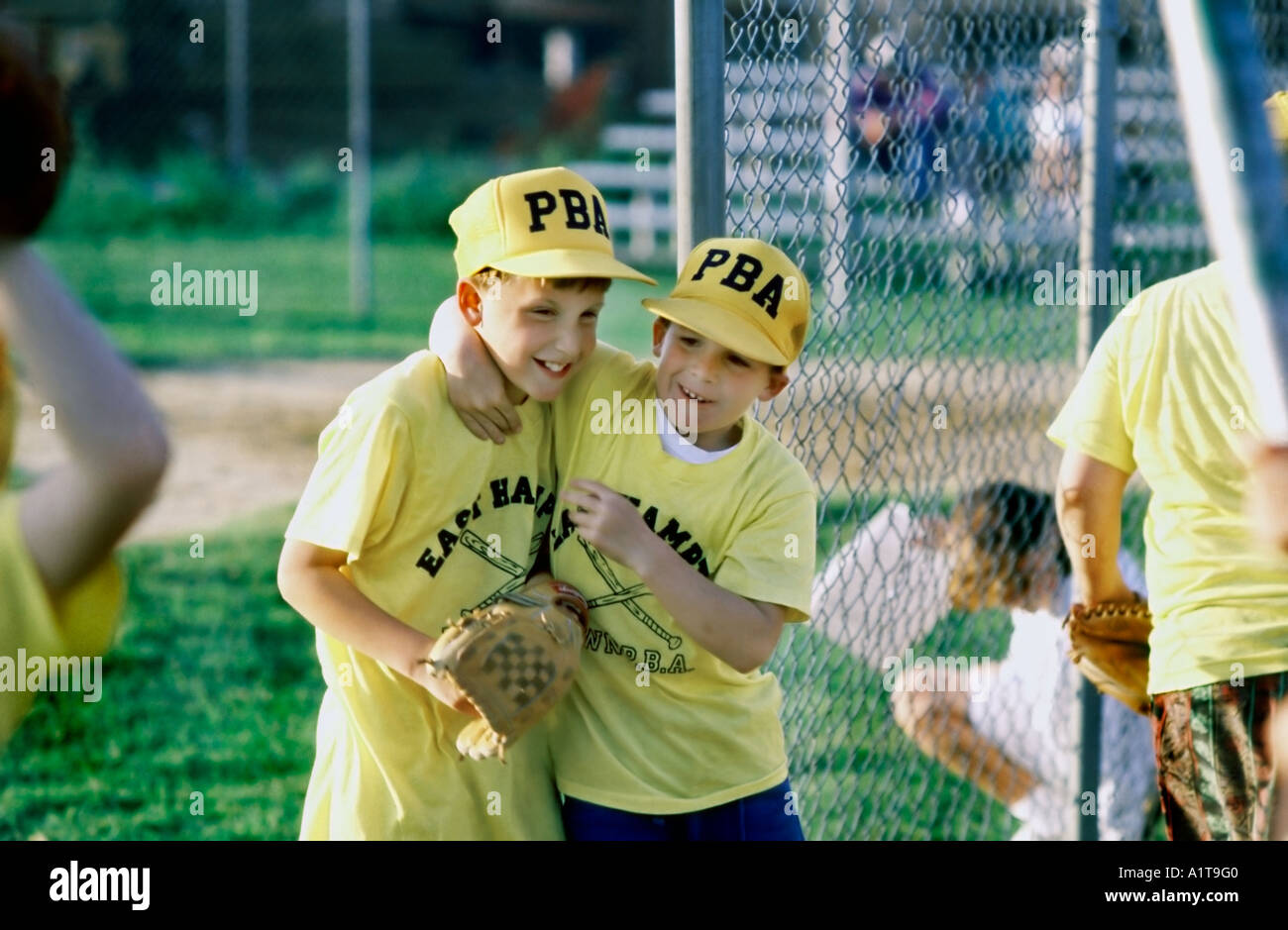 EAST HAMPTON, NY, USA, Two Young Teens, Umarmung bei Male Baseballspiel, Children Playing Game Outside Little League Uniforms Sport Stockfoto