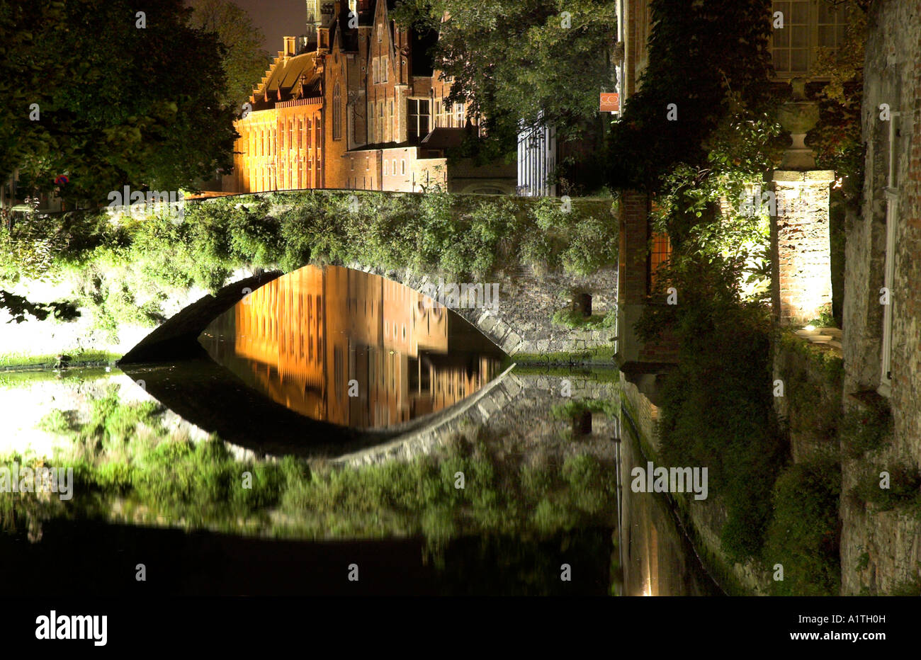 Eine Nachtaufnahme der mittelalterlichen Stadt Brügge mit den Gebäuden und Brücke perfekt in den Kanal wider Stockfoto