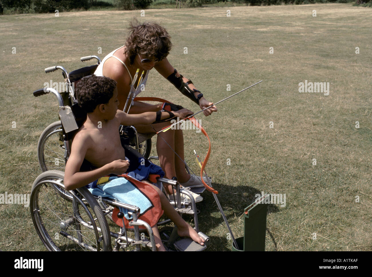 BEHINDERTEN JUNGEN UND LEHRER MIT BEHINDERUNG TUN BOGENSCHIEßEN 1989 Stockfoto
