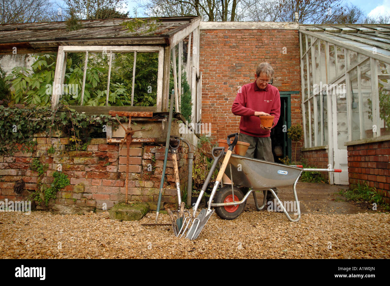 ein Gärtner arbeiten in einem ummauerten Garten in einem Landhaus Stockfoto