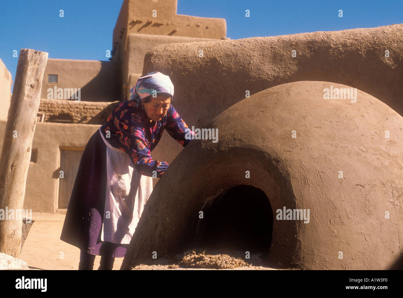 Taos New Mexico eine Frau Reparaturen im freien Adobe Ofen zum Backen von Brot, Fleisch und Kuchen in Taos Pueblo Stockfoto