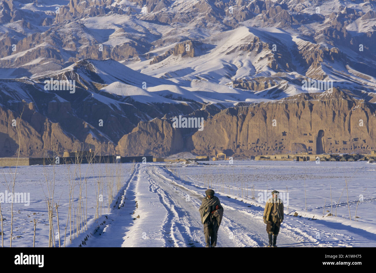 BAMIYAN AFGHANISTAN 1998 zwei Männer zu Fuß entlang schneebedeckte Straße vor Bergen und Felsen mit riesigen Buddha Stockfoto