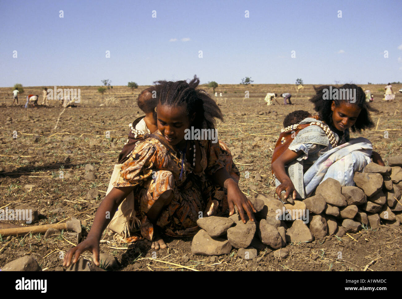 Zwei Frauen mit Babys auf dem Rücken Gebäude Bodenerosion Wände ERITREA MAI 1993 Stockfoto