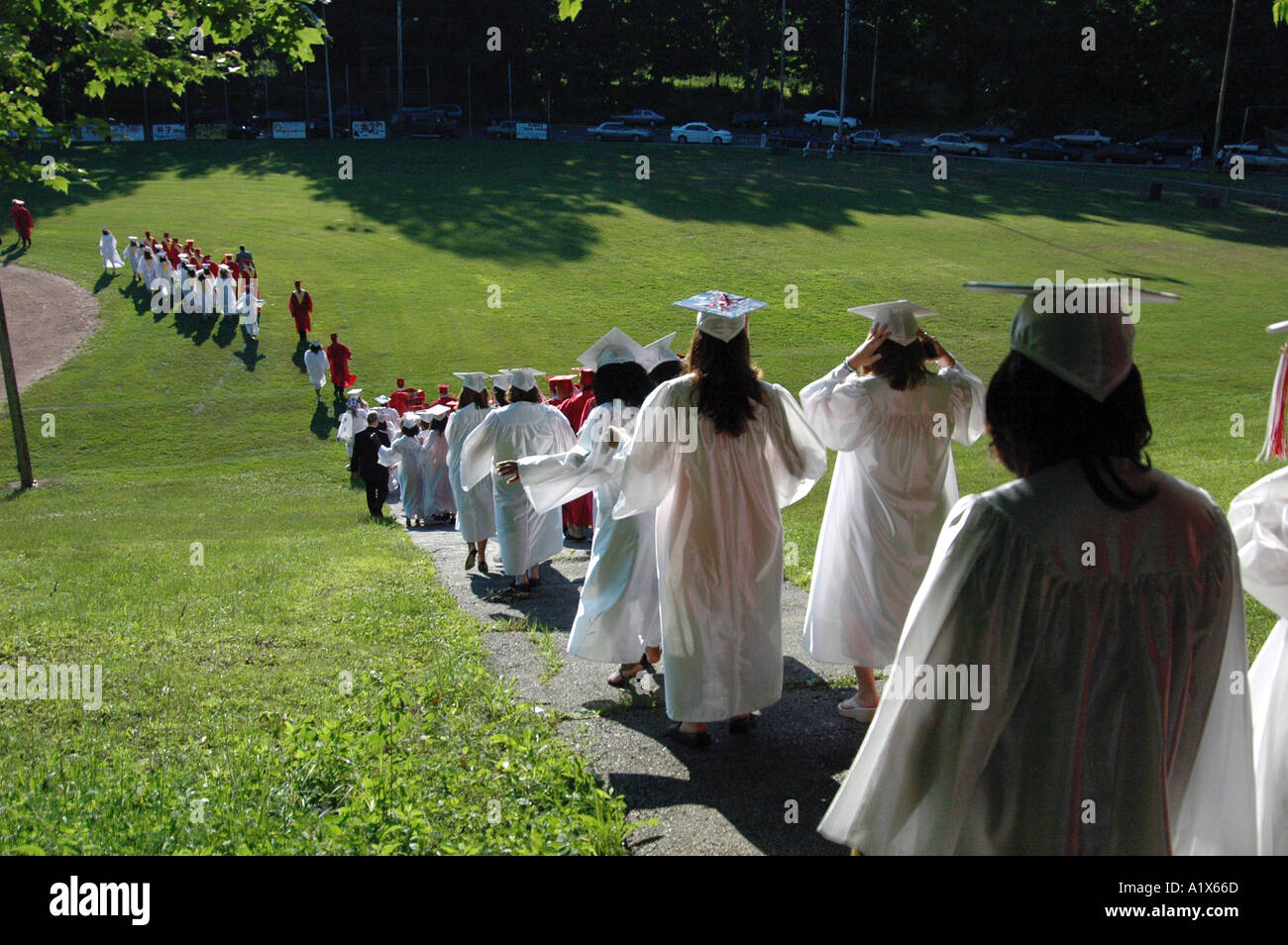Schüler zu Fuß einen Hügel hinunter zu Graduierung Zeremonie im freien Stockfoto