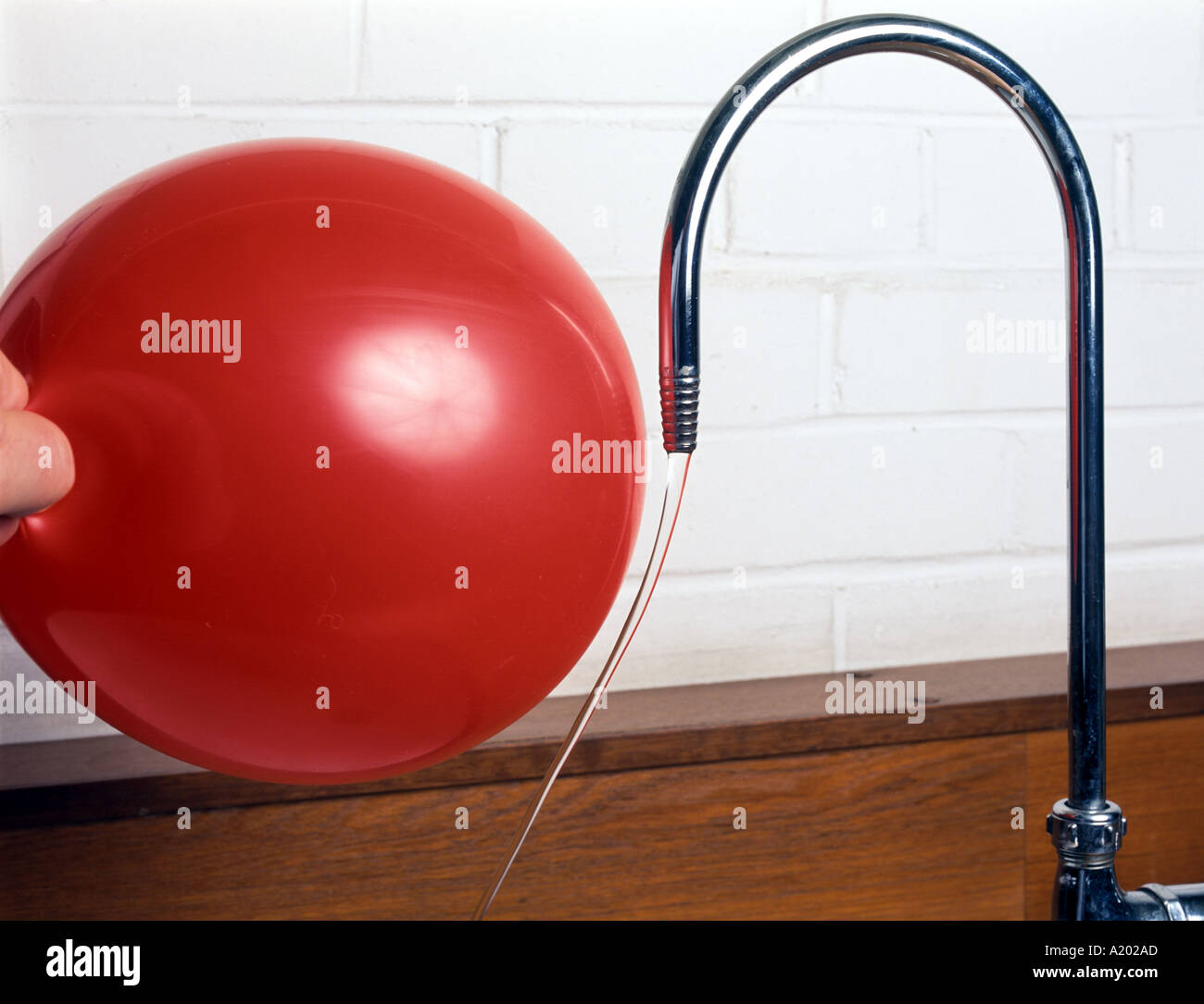 Durchbiegung von Bachwasser durch einen Ballon mit statischer Elektrizität aufgeladen Stockfoto