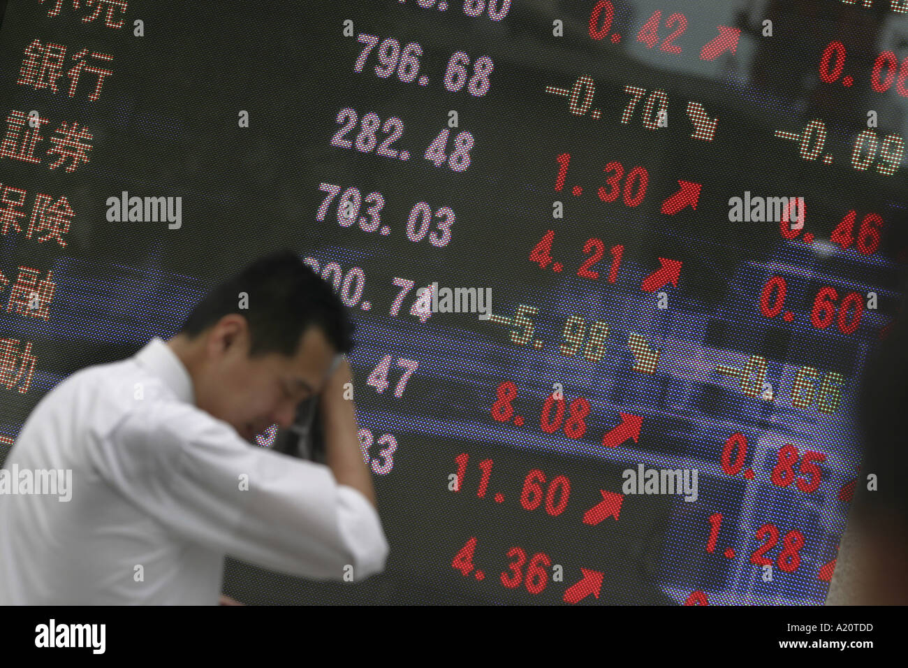 Japaner geht vorbei an einem Bank-Aktien und Aktien Monitorbildschirm zeigt die aktuellen Werte von Rohstoffen, Tokyo, Japan Stockfoto