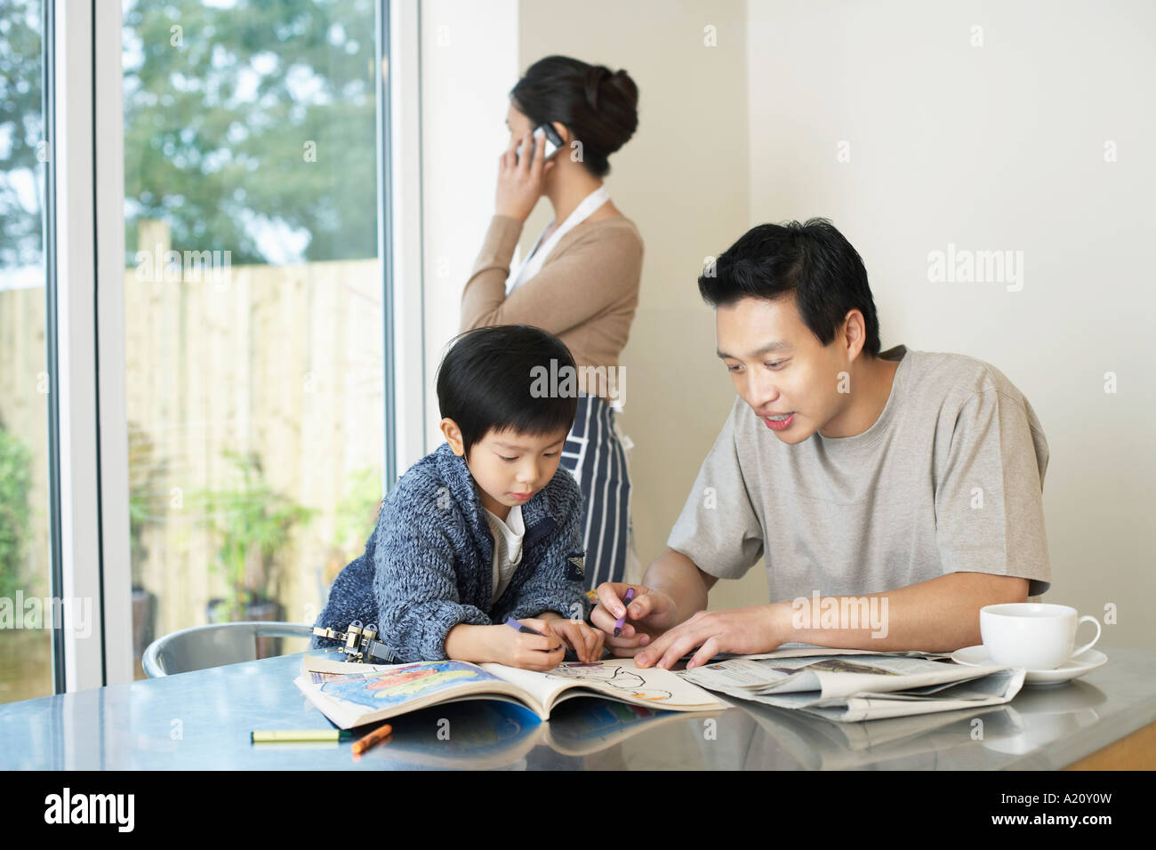 Vater und Sohn Färbung in Coloring Book auf Tisch, Mutter sprechen auf dem Handy Stockfoto