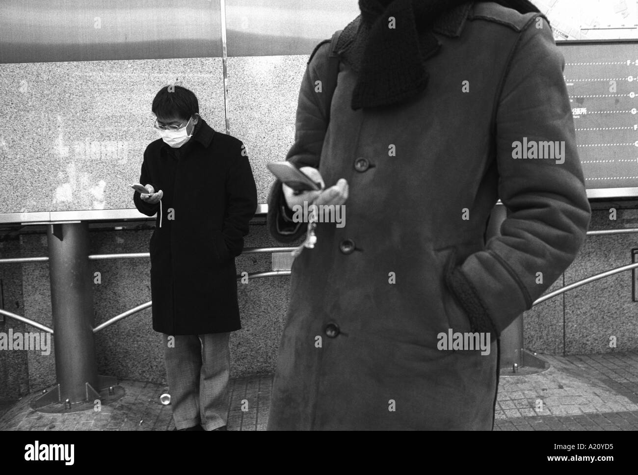 Zwei Japaner mit ihrer Telefone für SMS, Shibuya, Tokyo, Japan. Stockfoto