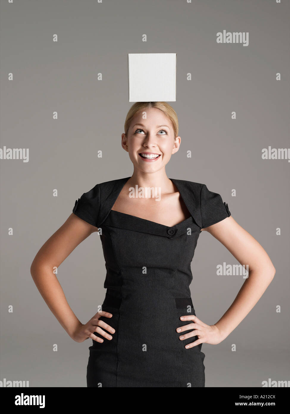 Junge Frau im schwarzen Kleid mit weißen Kasten auf dem Kopf Stockfoto