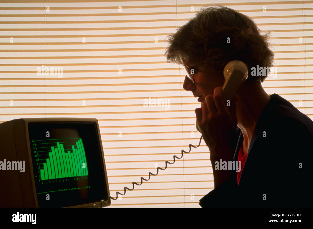 Silhouette der Frau mit Telefon beim Sitzen am computer Stockfoto