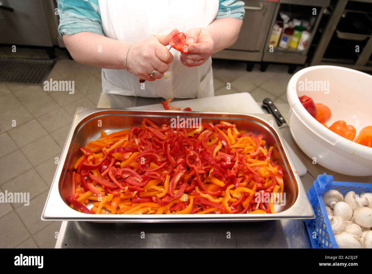 Küche Hilfe schneiden Paprika in Schule Großküche, Gemüse in Schüsseln Stockfoto