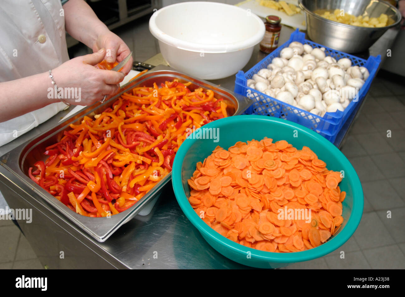 Küche Hilfe schneiden Paprika in Schule Großküche, Gemüse in Schüsseln Stockfoto