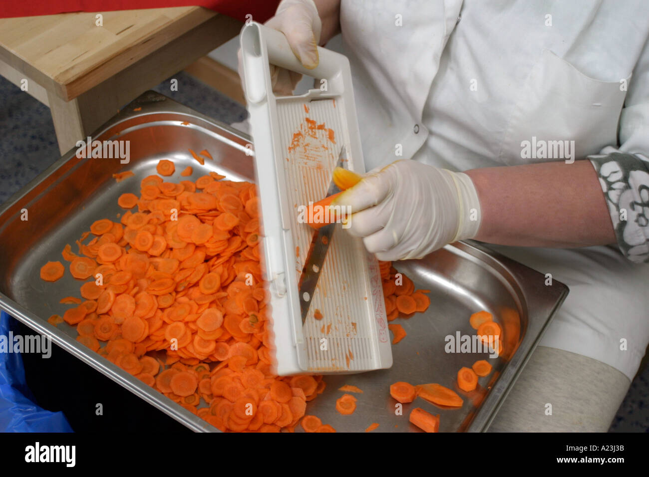 Küche Hilfe schneiden Karotten in Schule Großküche, Gemüse in Schüsseln Stockfoto