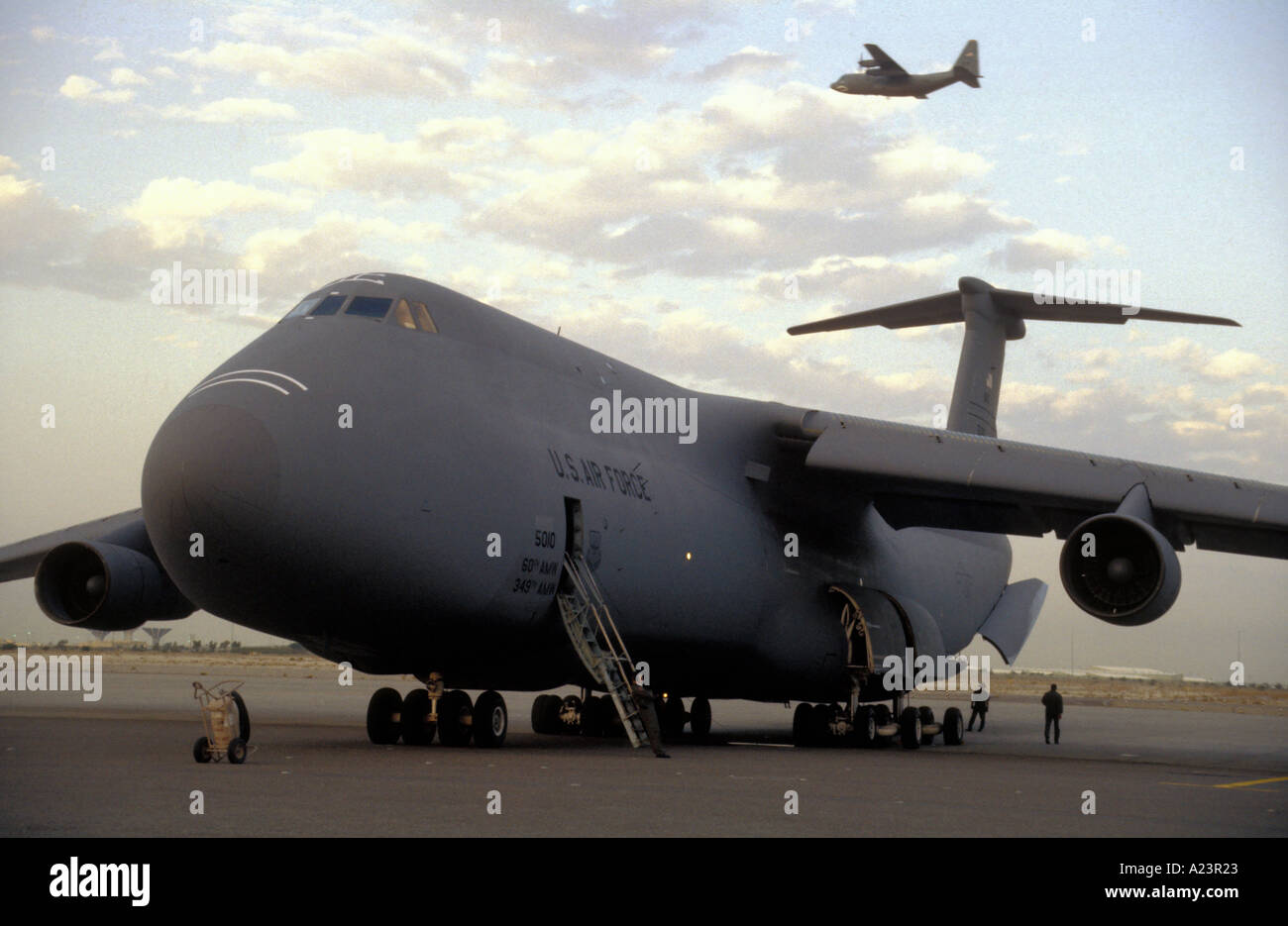 Ein USAF-C5-Galaxy bereitet zum Entladen der Fracht in Kuwait, während oben ein C130 Luft bekommt Stockfoto